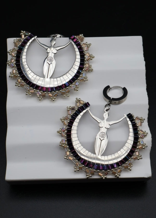 Pair of silver and purple earrings on a white stand with a black background