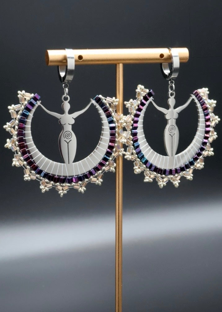 Pair of intricate earrings on a stand against a dark background