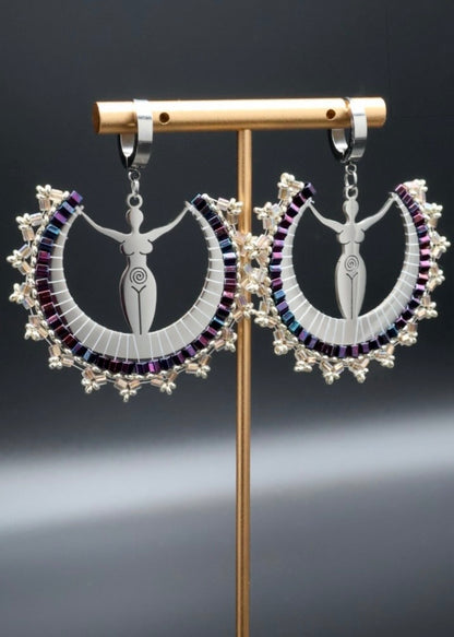 Pair of intricate earrings on a stand against a dark background