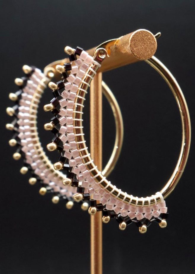 Gold hoop earrings with bead detailing on a black background