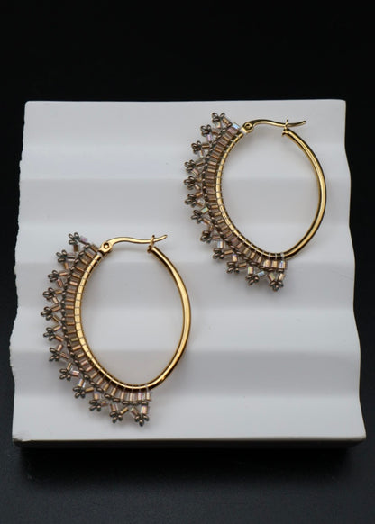 Gold hoop earrings with intricate designs on a white surface