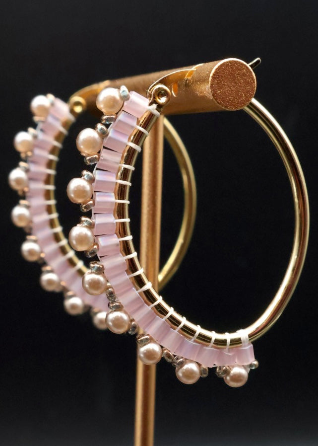 Gold hoop earrings with pearl accents on a black background