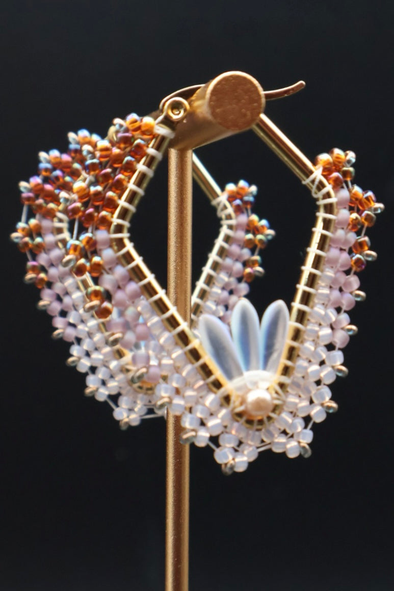 Decorative earring on a stand with intricate design against a black background