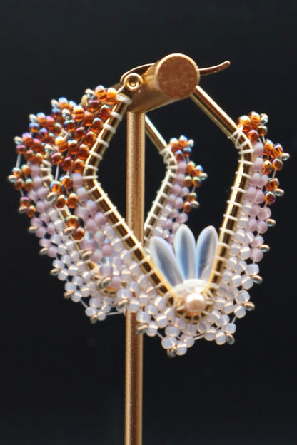 Decorative earring on a stand with intricate design against a black background