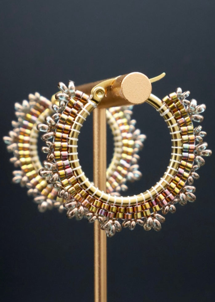 Gold hoop earrings with beaded detailing on a dark background