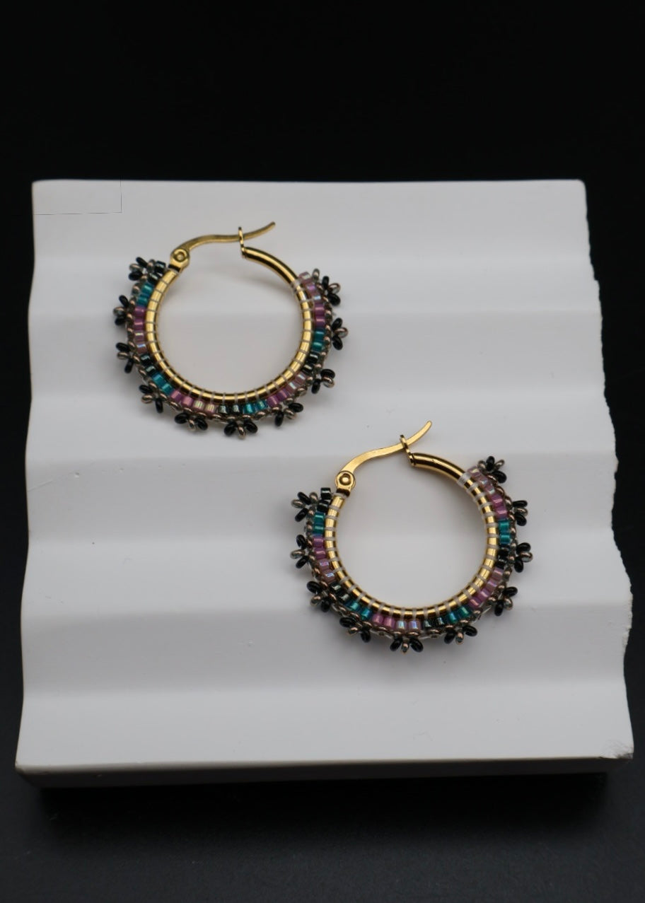 Pair of hoop earrings with multicolored stones on a white surface