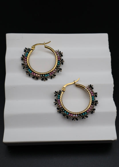 Pair of hoop earrings with multicolored stones on a white surface