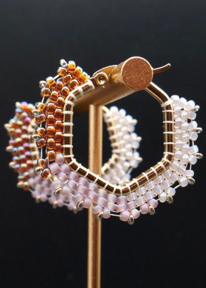 Gold and beaded hoop earrings on a black background