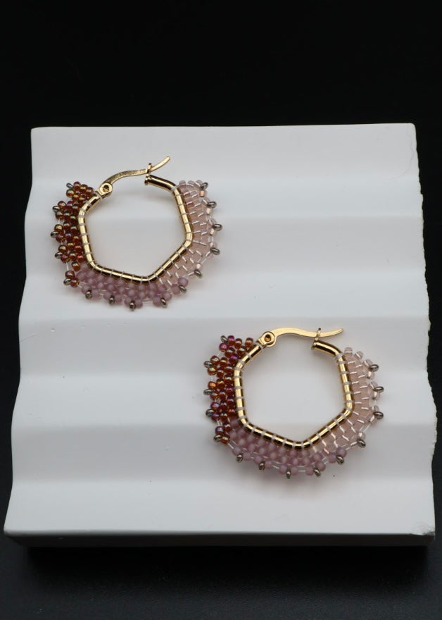 Pair of gold hoop earrings with bead detailing on a white surface.