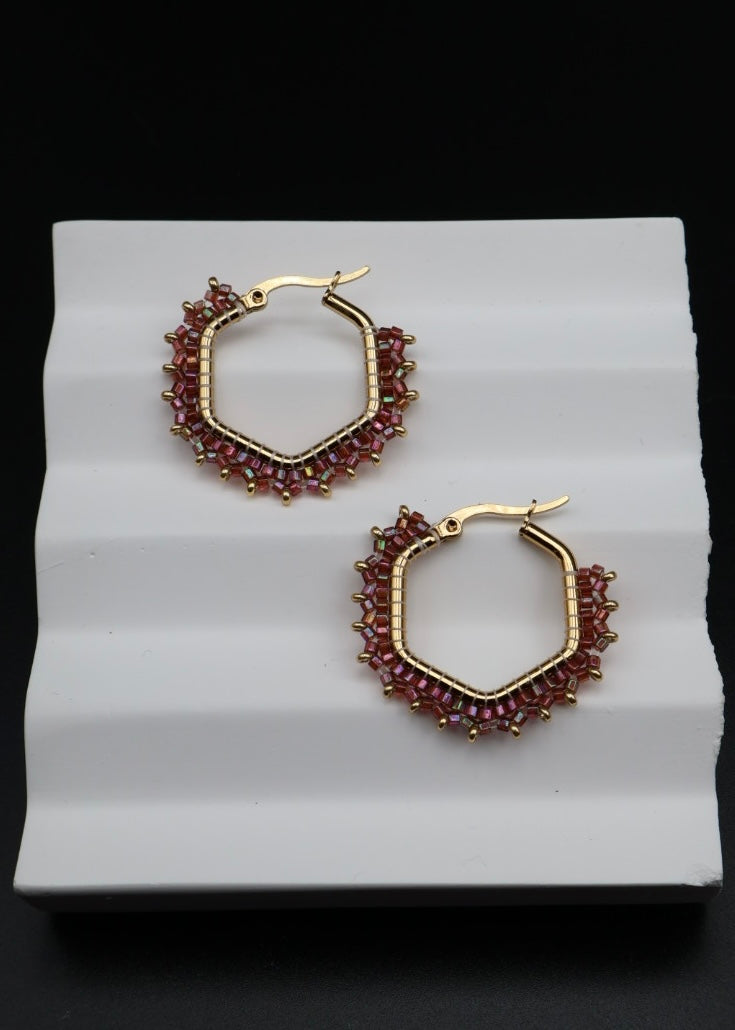 Gold hoop earrings with red gemstones on a white background