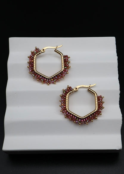 Gold hoop earrings with red gemstones on a white background