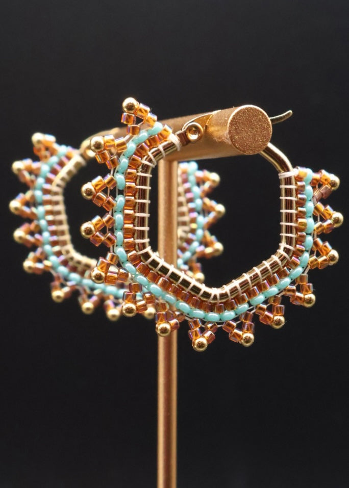 Gold and turquoise hoop earrings on a black background