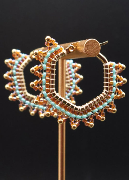 Gold and turquoise hoop earrings on a black background