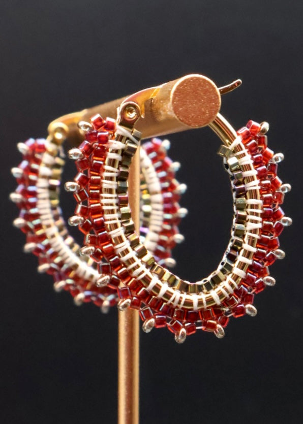 Hoop earrings with red and gold beads on a black background