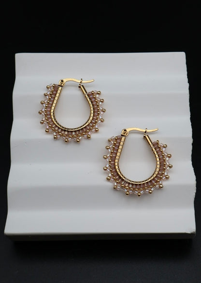 Pair of gold hoop earrings on a white stand with a black background
