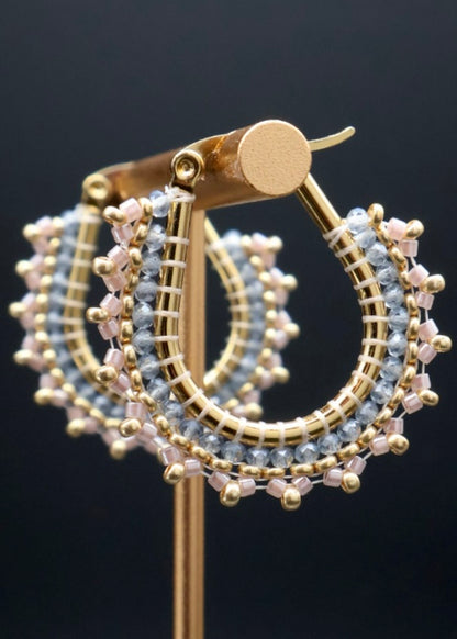 Gold hoop earrings with bead detailing on a black background