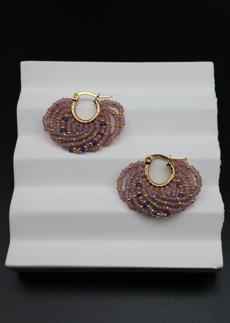 Pair of beaded earrings on a white stand with a black background