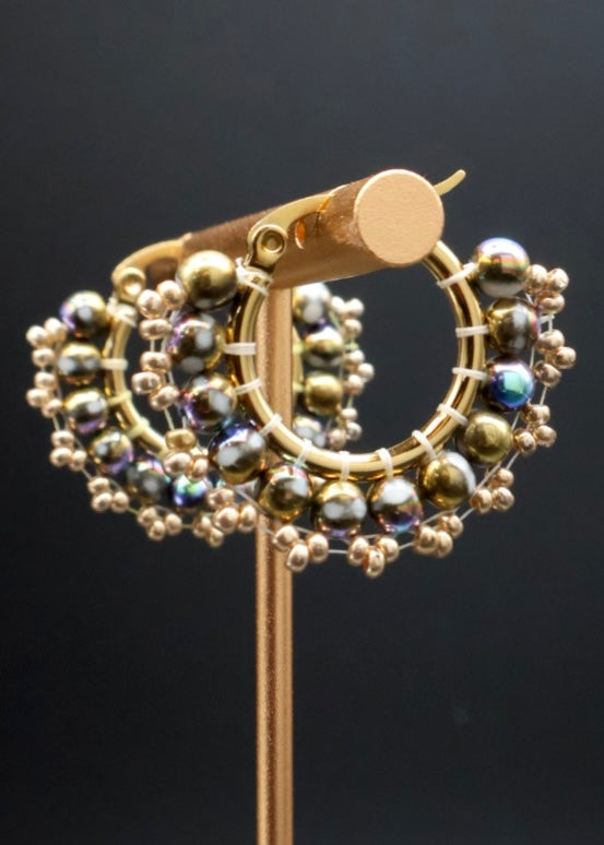 Gold earring with bead detailing on a black background