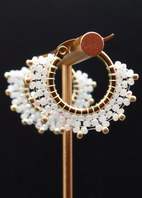 Decorative brooch with gold and white bead design on a black background