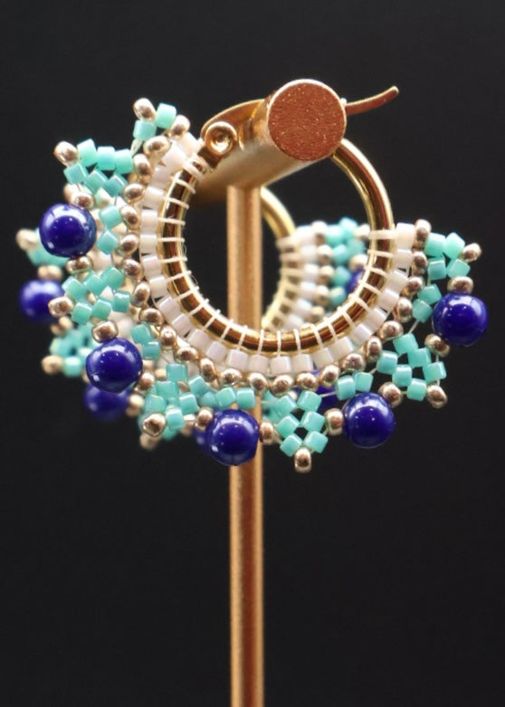 Decorative brooch with blue and gold design on a black background