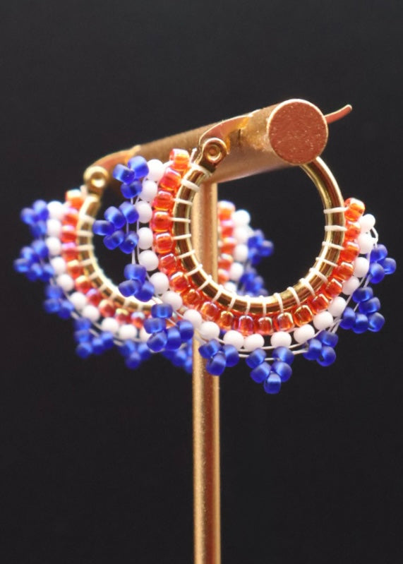 Beaded hoop earrings with blue, orange, and white beads on a black background