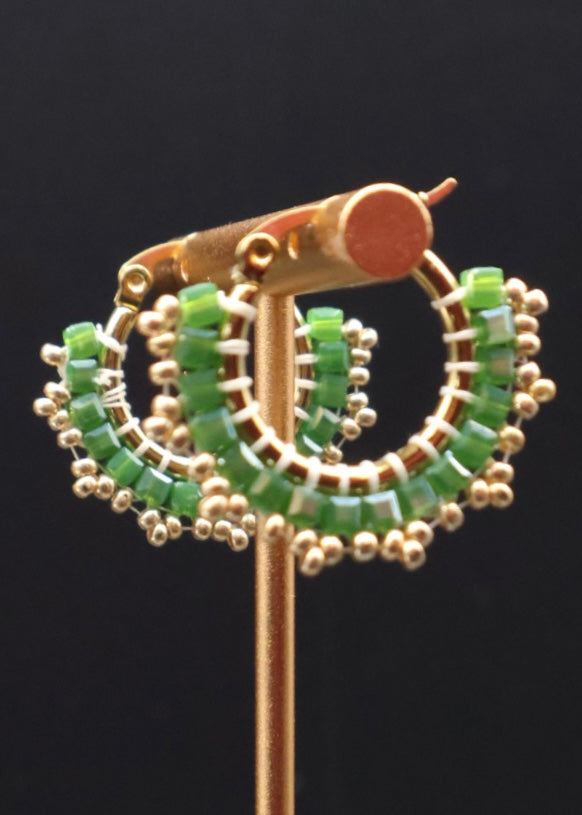 Gold and green beaded earring on a black background