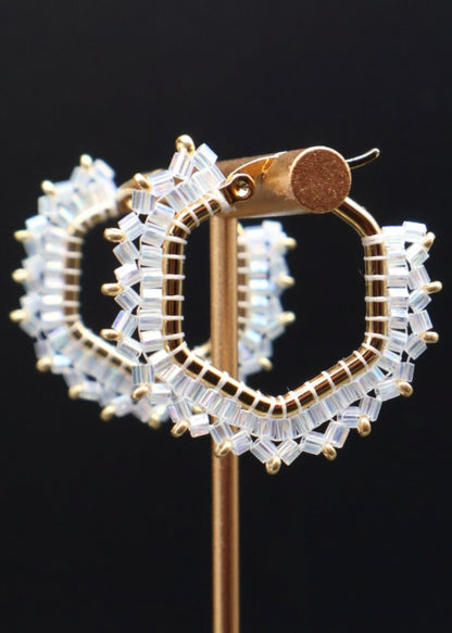 Gold hoop earrings with clear gemstones on a black background