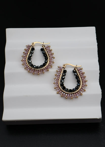 Pair of hoop earrings with gemstones on a white stand against a black background