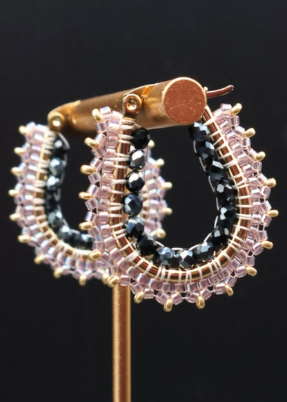 Decorative brooch with circular design featuring black and clear gemstones on a dark background