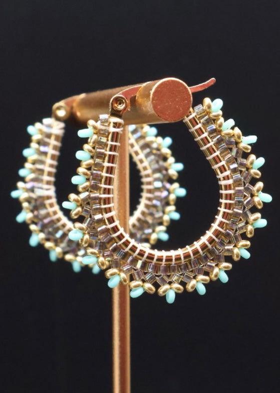Pair of hoop earrings with turquoise beads on a black background