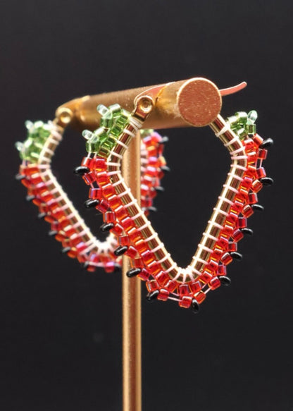 Hoop earrings with red and green gemstones on a black background