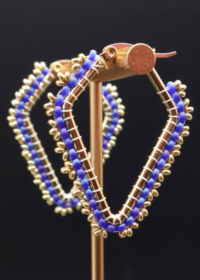 Gold hoop earrings with blue beads on a black background
