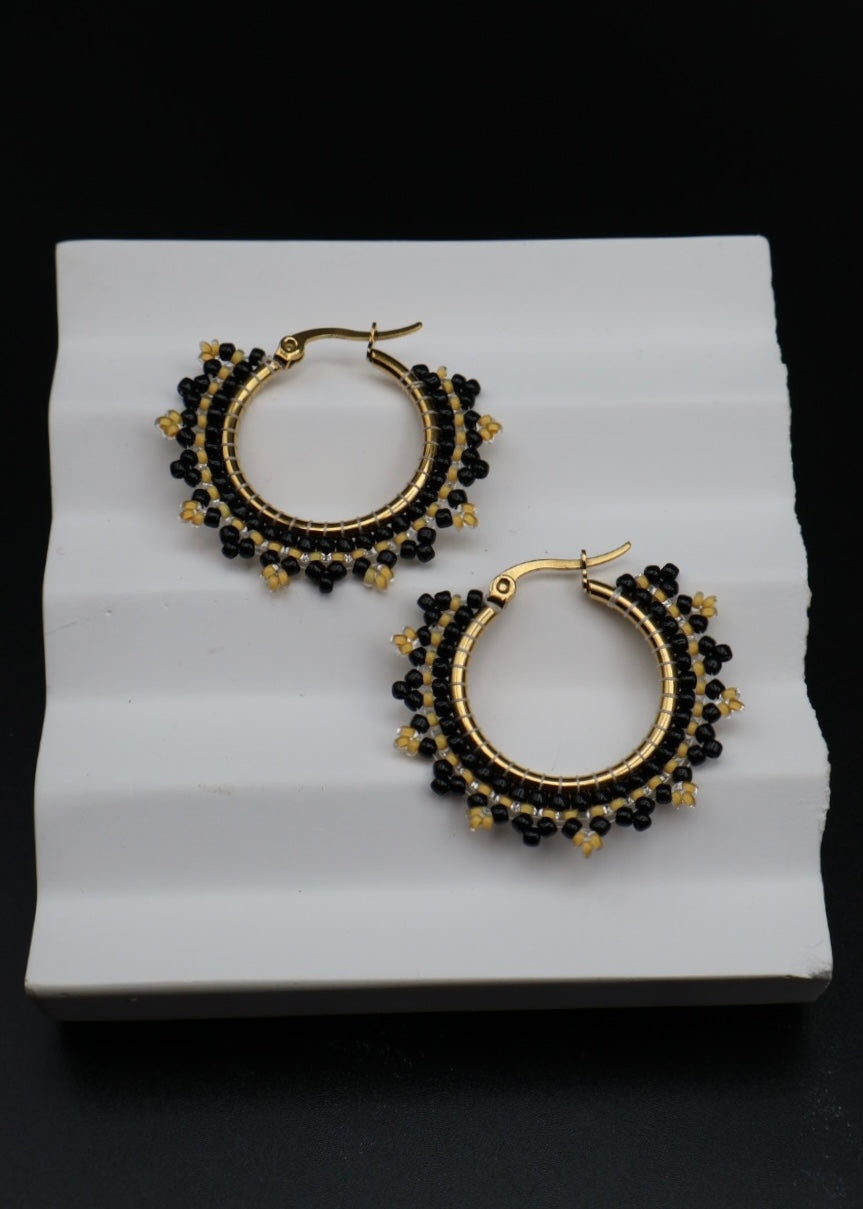 Gold and black hoop earrings on a white surface with a black background