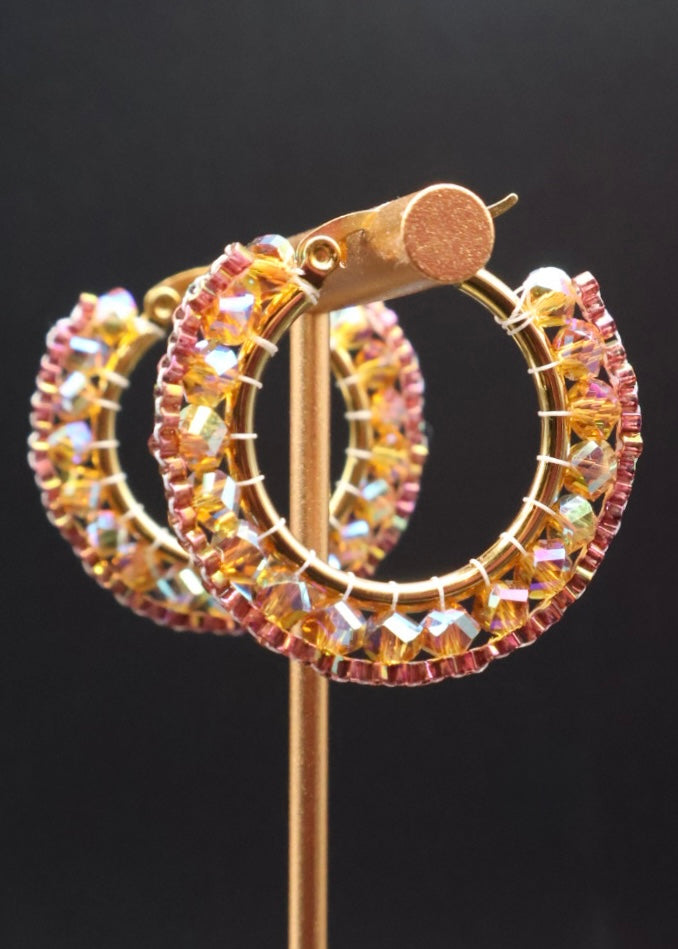 Gold hoop earrings with colorful beads on a black background