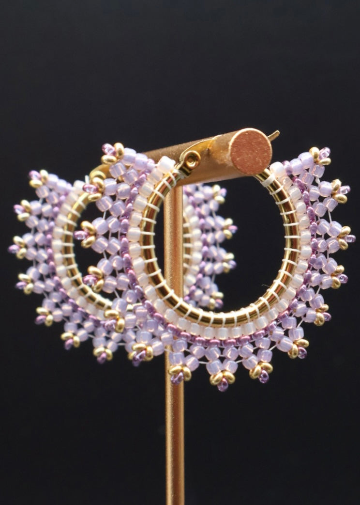 Gold and purple beaded earrings on a black background