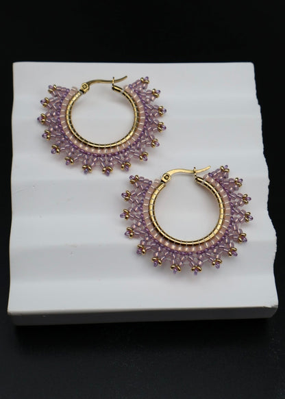 Pair of purple hoop earrings with gold accents on a white stand.