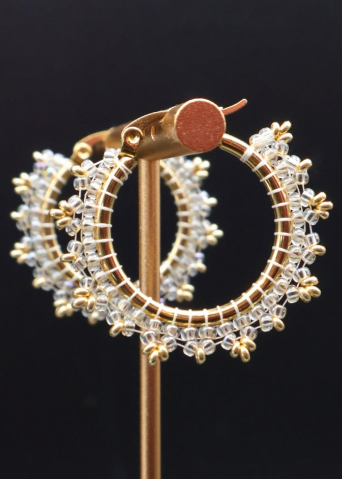 Gold hoop earrings with clear gemstones on a black background