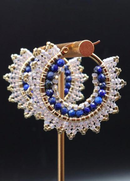 Gold, blue, and clear beaded earrings on a black background