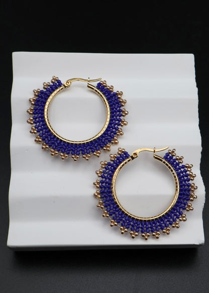 Pair of blue hoop earrings with gold accents on a white surface.