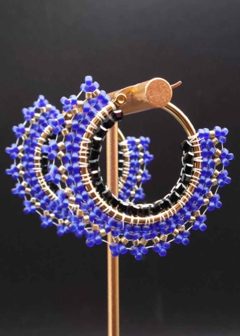 Earring with blue and black beads on a dark background
