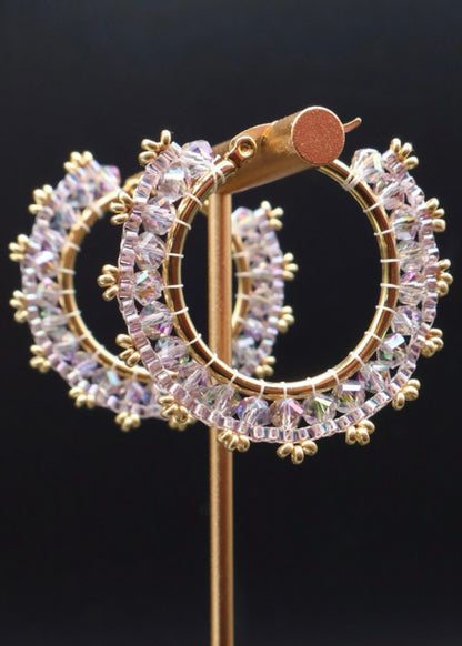 Gold hoop earrings with clear gemstones on a black background