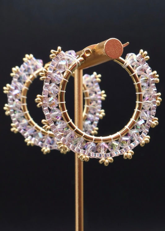 Gold hoop earrings with clear gemstones on a black background