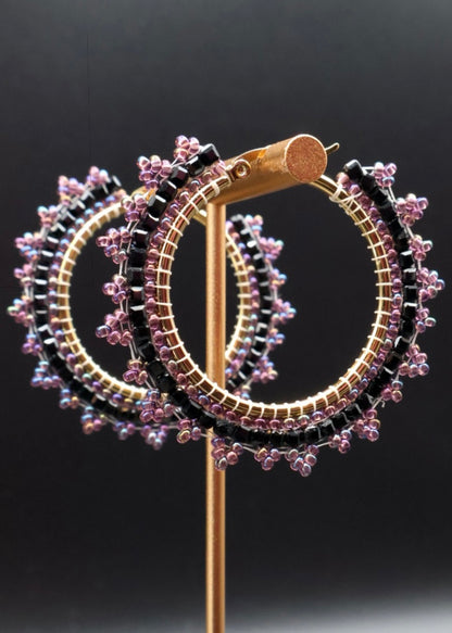 Pair of hoop earrings with floral detailing on a black background