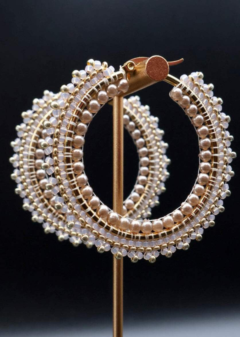 Gold and pearl hoop earrings on a black background