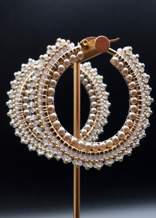 Gold and pearl hoop earrings on a black background