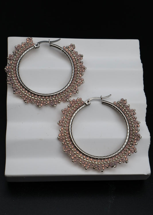 Pair of silver hoop earrings on a white platform with a black background