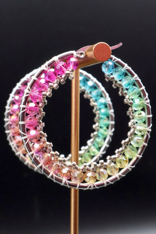 Colorful beaded hoop earrings on a black background