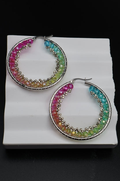 Multicolored hoop earrings on a white stand with a black background