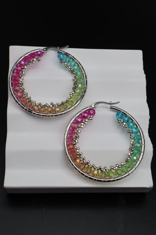 Multicolored hoop earrings on a white stand with a black background