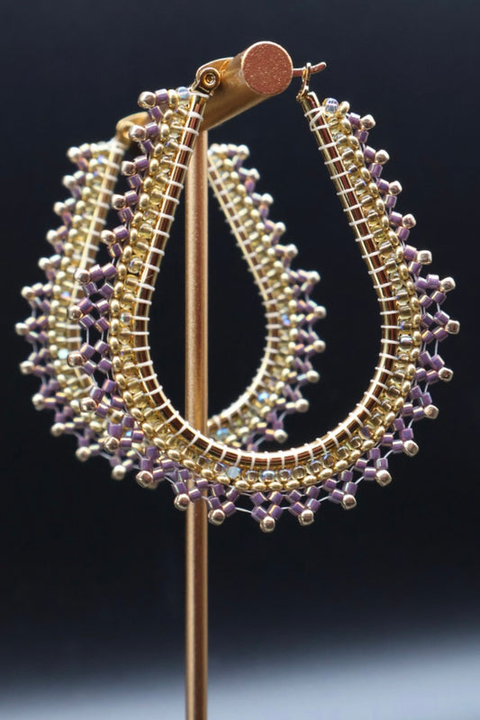 Decorative earring on a stand with intricate design against a dark background
